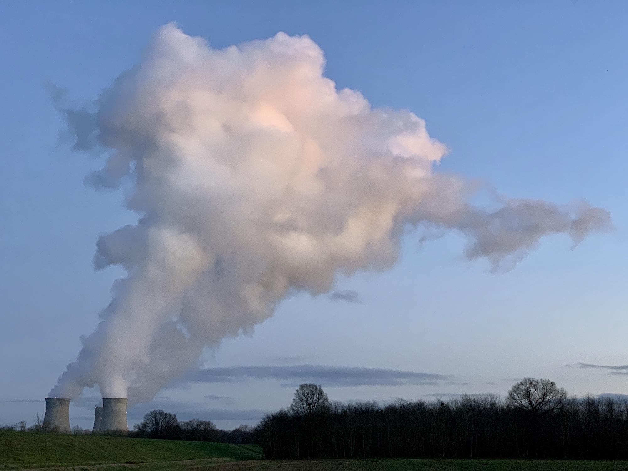 Nuage de vapeur s'échappant d'une centrale se découpant sur un ciel bleu à la tombé du jour.