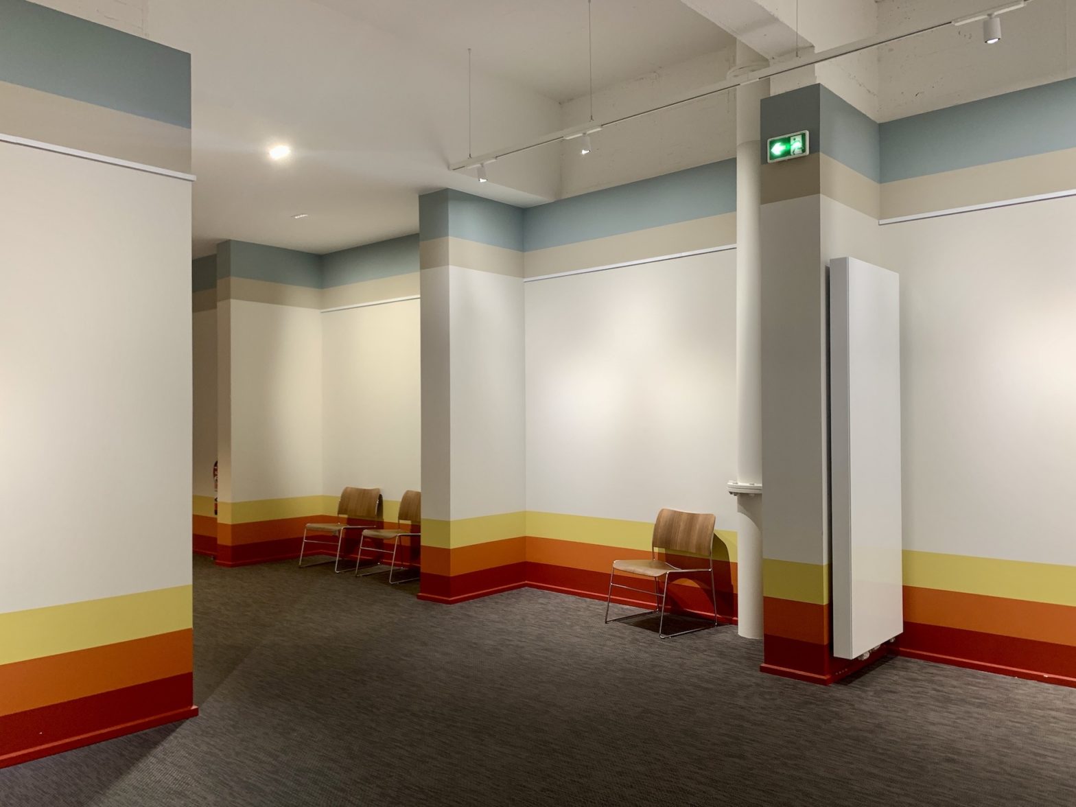 Photo d'un couloir d'un centre de conférence avec des rayures très graphique aux murs, bleus en haut et orangé en bas.