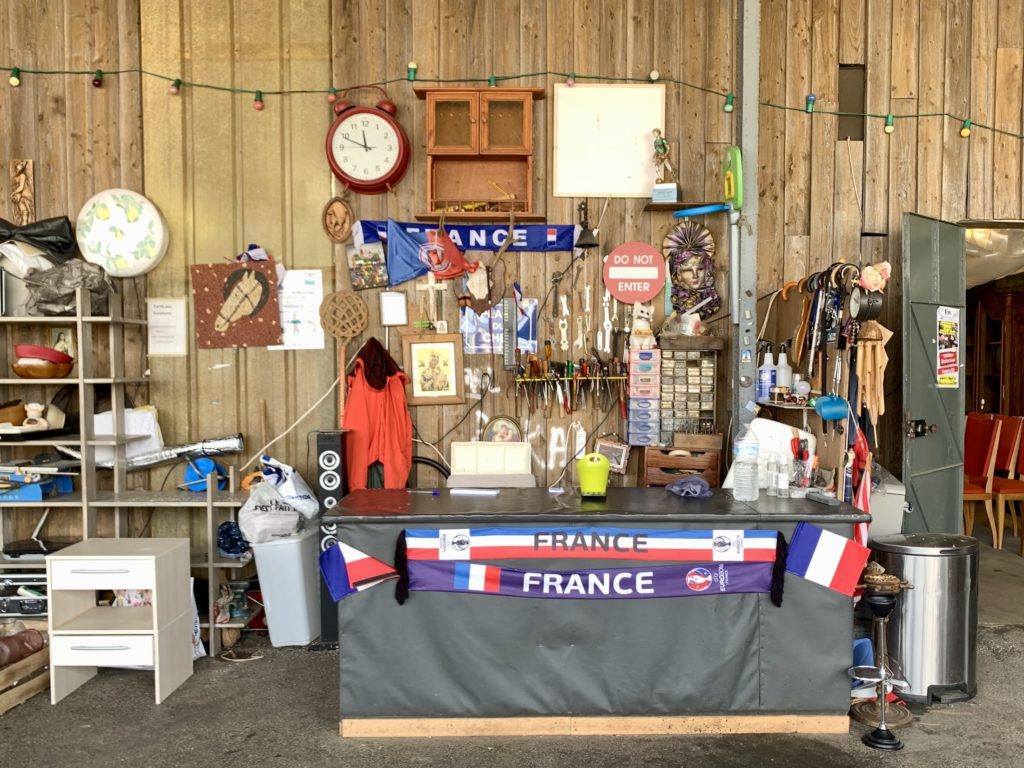 Une caisse d'Emmaus, décorée de tout un bric à brac et d'écharpe de l'équipe de France de foot. 